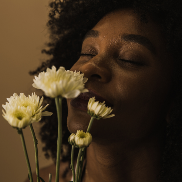 Woman sniffing white flowers for aromatherapy.