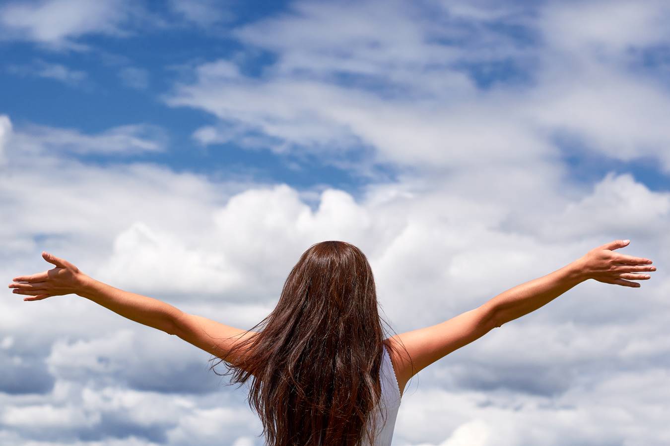 Woman with her arms stretched out looking at the sky.