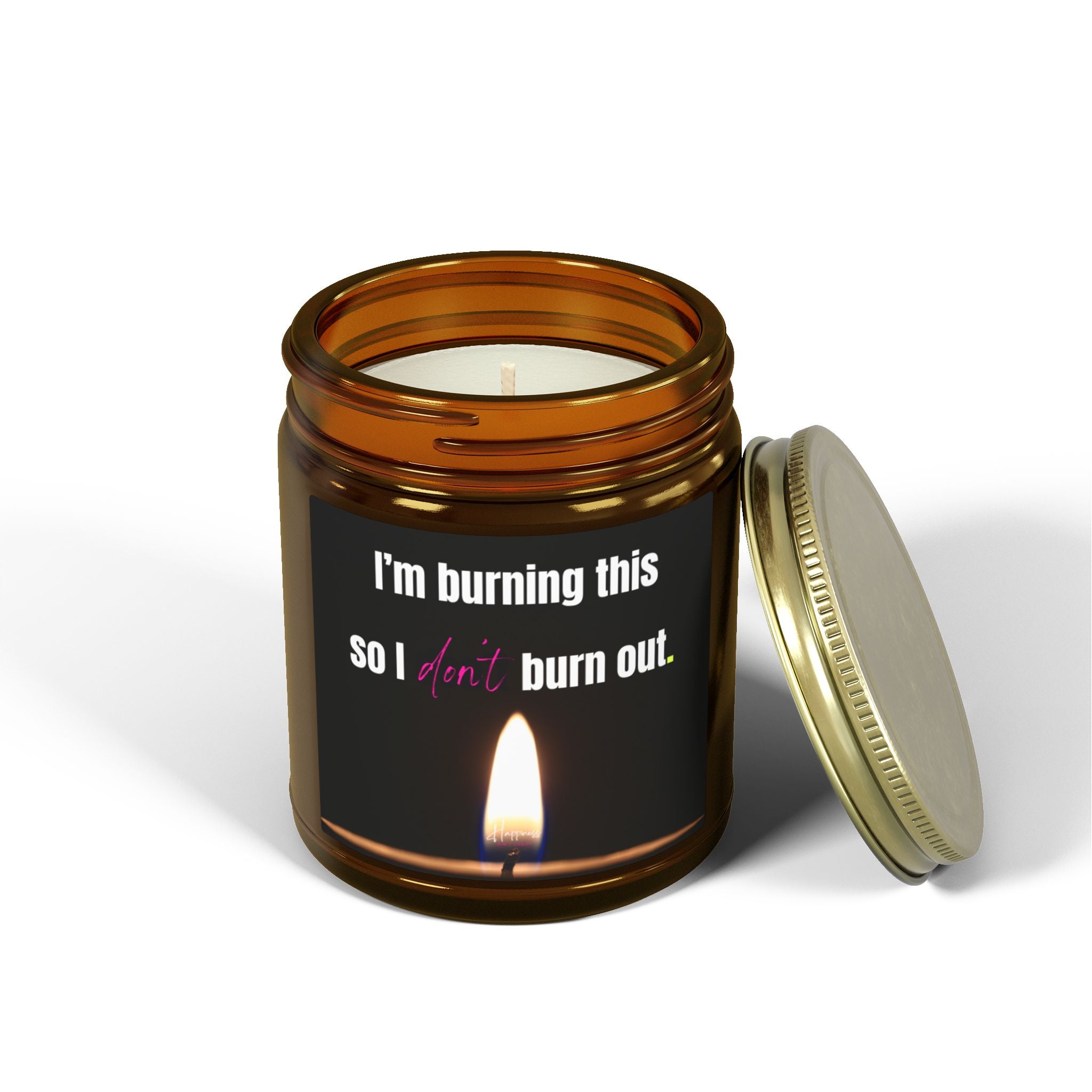 Candle in an amber glass jar with a gold lid and a label that says 'I'm burning this so I don't burn out' on a white background