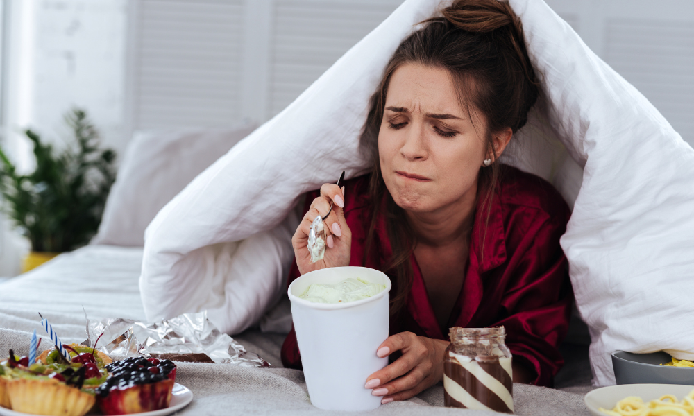 Woman sad while stress-eating snacks and sweets.